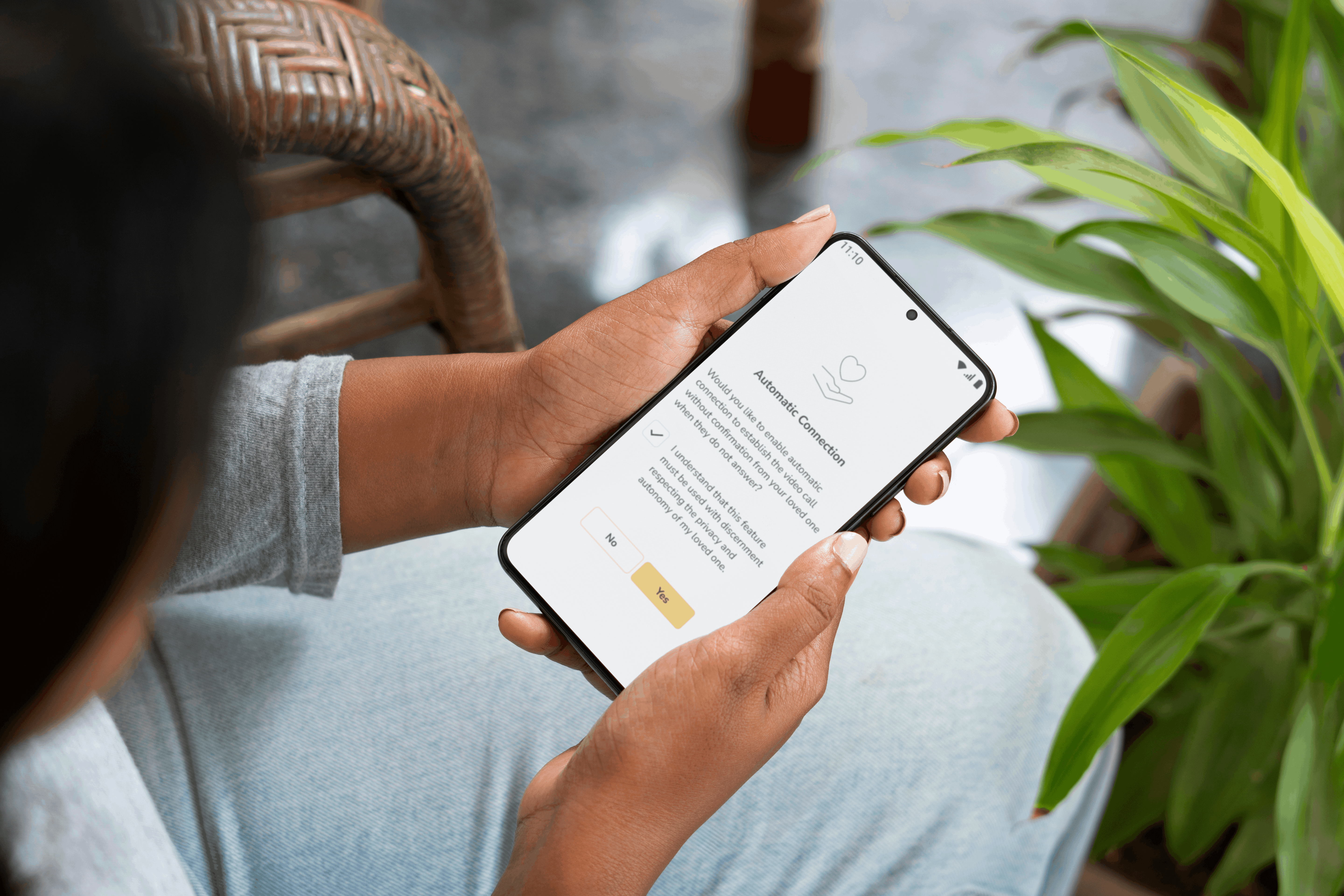 woman holding a phone that shows the ethical confirmation step for caregivers for the new Auto Connect feature that is available to premium subscribers of the Idem Smart Clock