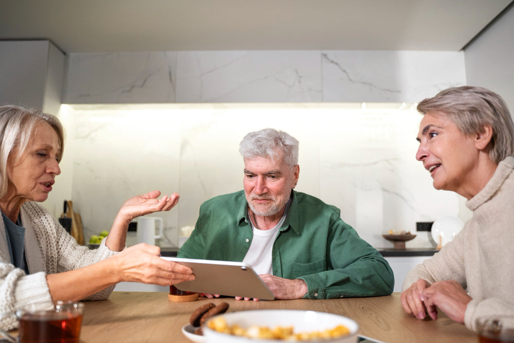 A man holding a tablet, talking with two woman.