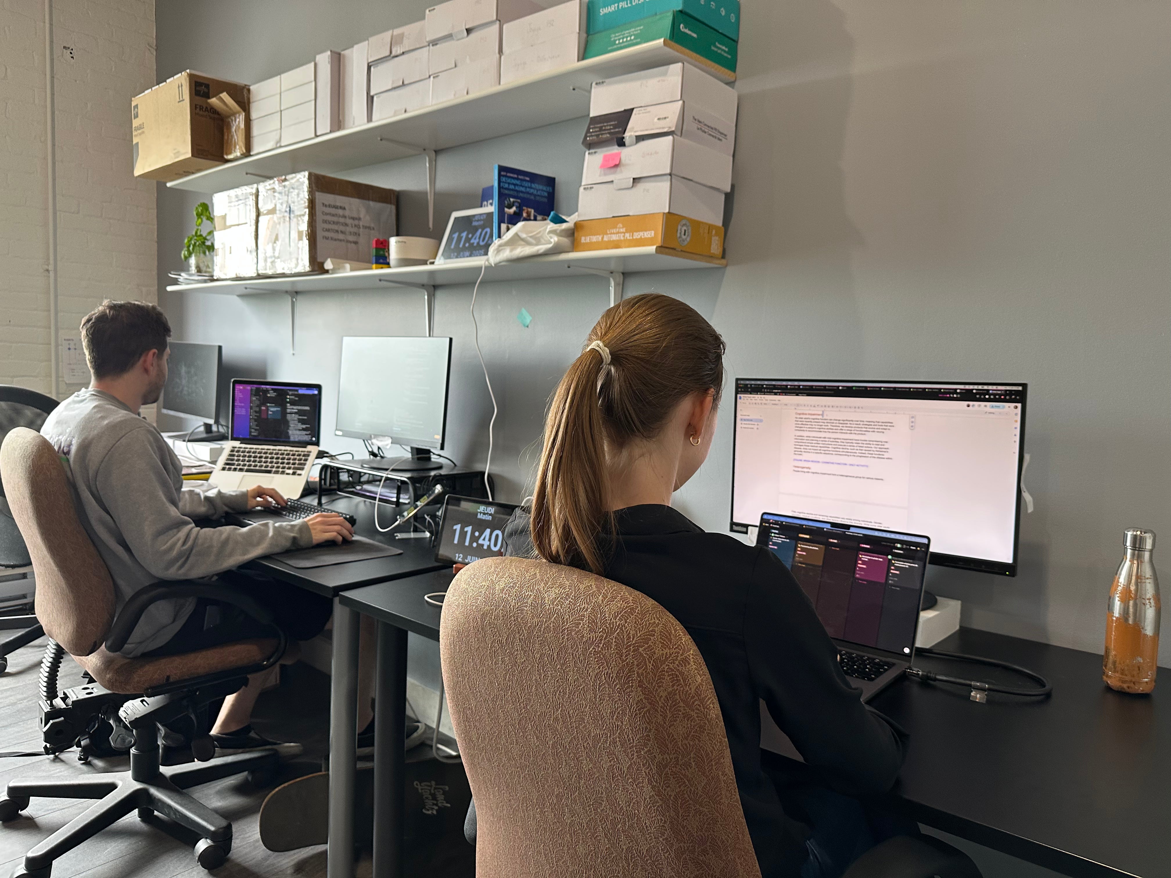 Two people working at desks with computers in an office setting.