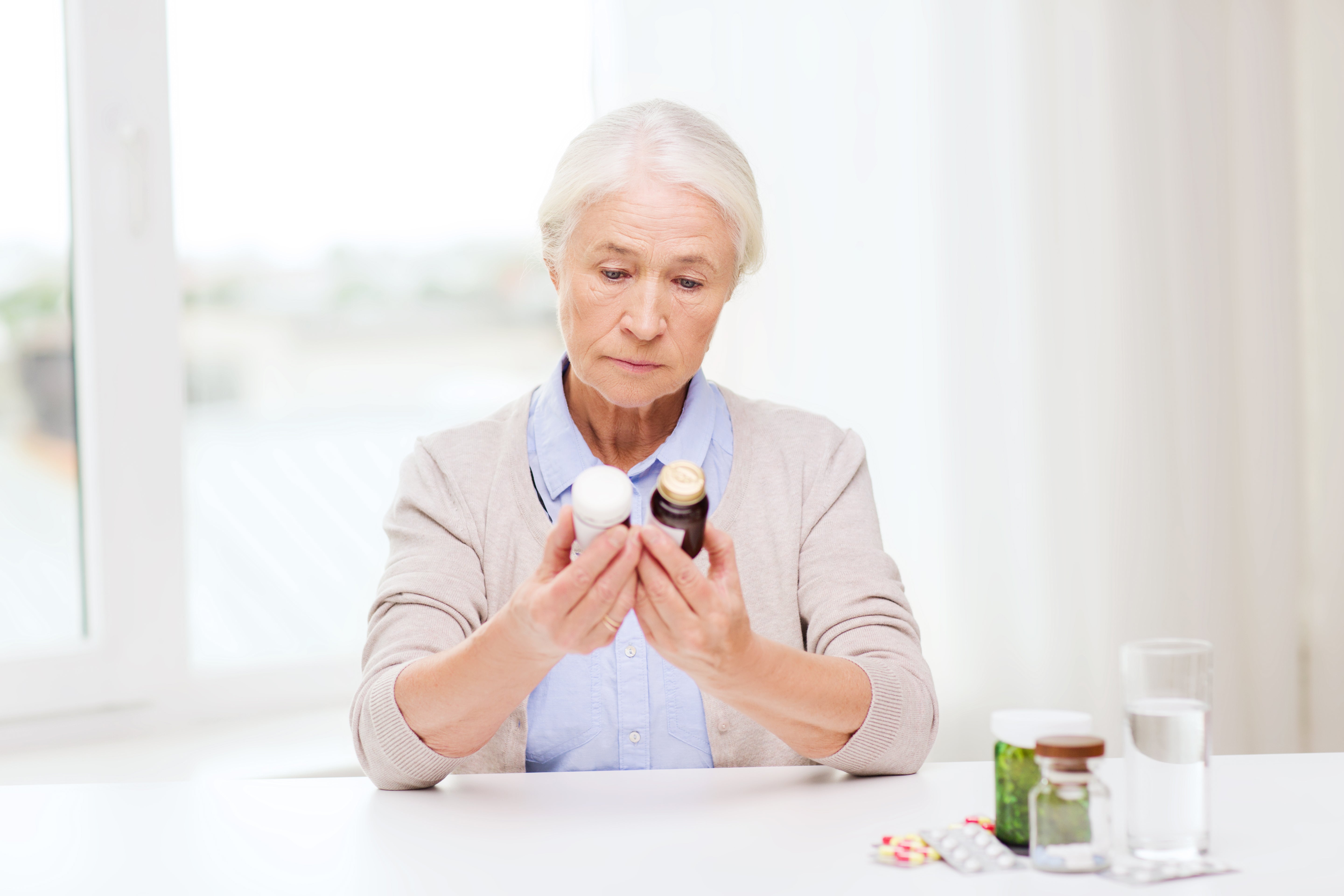 Senior woman holding a bottle of pills in a bright room