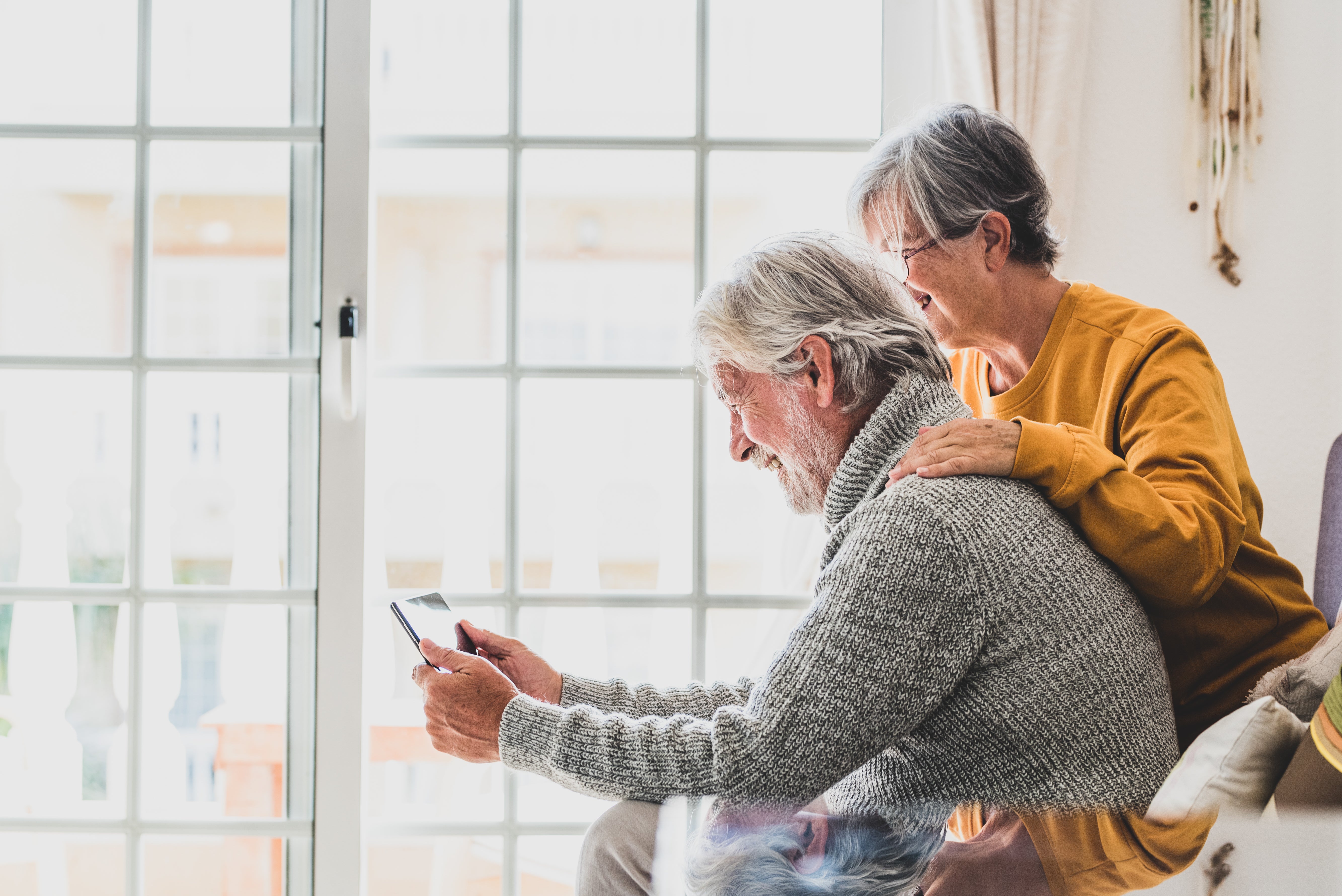 Two elderly people sitting together, one using a Idem Smart Clock
