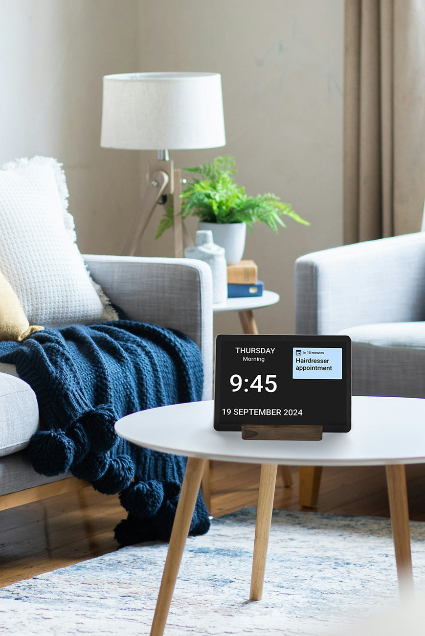 The Idem Clock on a table in a living room with an appointment displayed on the clock